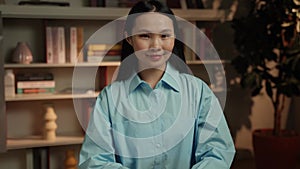 Smiling Young Woman in Blue Shirt Standing in a Cozy Home Library