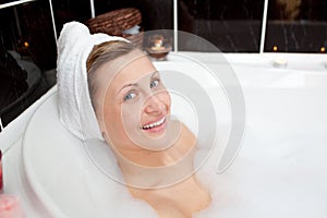Smiling young woman in a bubble bath