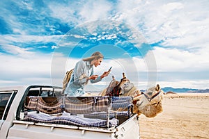 Smiling young woman in car takes photo of camel in the Middle of the Wadi Rum desert in Jordan