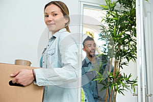 Smiling young woman carrying cardboard box