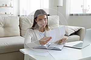 Smiling young woman checking post mail at home.