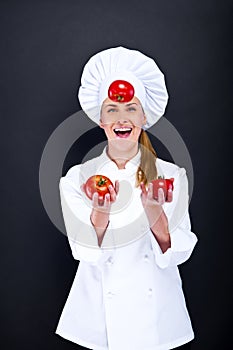 Smiling young woman chef with tomatos juggle