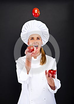 Smiling young woman chef with tomatos juggle