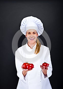 Smiling young woman chef with tomatos juggle