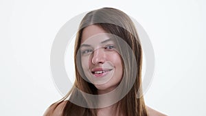 Smiling young woman combing hair on white background