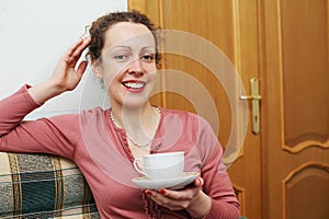 A smiling young woman with a cup and saucer in