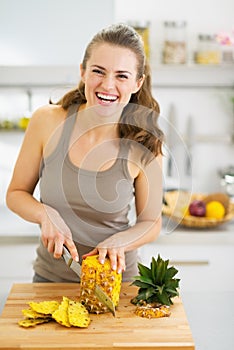 Smiling young woman cutting pineapple