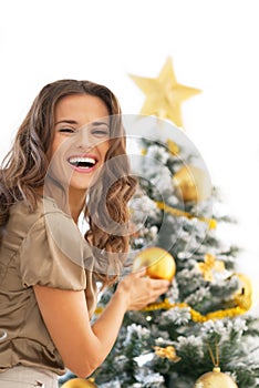 Smiling young woman decorating christmas tree