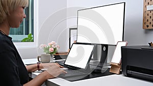 Smiling young woman designer using multiple device at modern office.