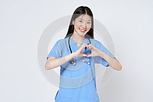 Smiling young woman doctor makes a heart shape with her hand isolate on white background