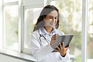 Smiling young woman doctor using digital tablet