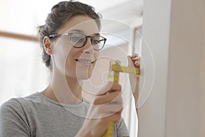 Smiling woman doing a home makeover and measuring with a ruler photo