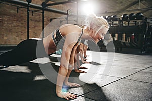 Smiling young woman doing pushups during an exercise class