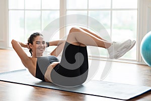 Smiling Young Woman Doing Sit-ups Exercise With Leg Raise