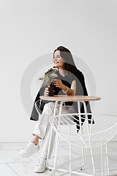 Smiling young woman dressed casual business style enjoy her lifestyle. Happy confident woman is sitting at table on