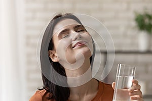 Smiling young woman drink mineral water from glass