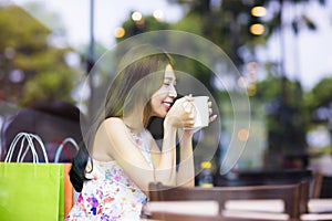 Smiling young woman drinking coffee in cafe shop