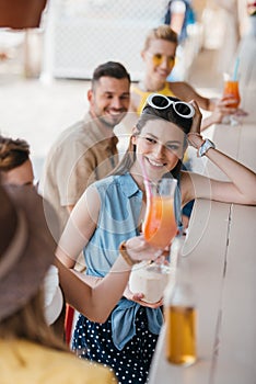 smiling young woman drinking summer cocktail with friends