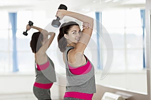 Smiling young woman with dumbbells in the gym. Active lifestyle and health