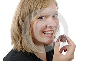 Smiling young woman eating a chocolate candy