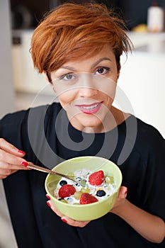 Smiling young woman eating fresh fruits