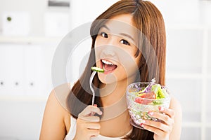 Smiling young woman eating fruits and salad.