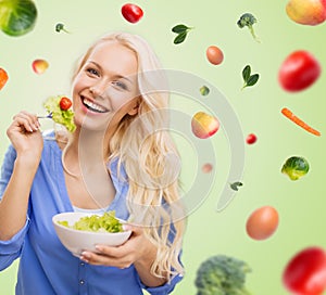 Smiling young woman eating green vegetable salad