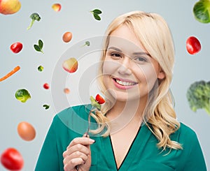 Smiling young woman eating vegetable salad