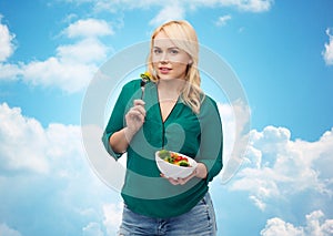 Smiling young woman eating vegetable salad