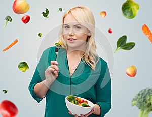 Smiling young woman eating vegetable salad