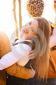 Smiling Young Woman Embraced by Friend in Sunlit Setting
