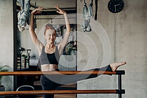 Smiling young woman enjoying barre workout in studio