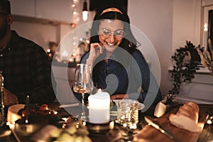 Smiling young woman enjoying a candlelit dinner party with frien