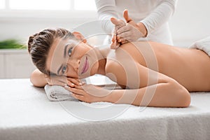 Smiling young woman enjoying healing back massage