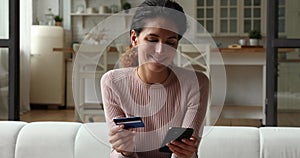 Smiling young woman enjoying shopping online at home.