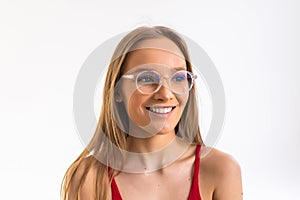 Smiling young woman in eyeglasses posing with crossed arms and looking at the camera over white background