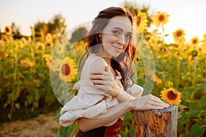 Smiling young woman in a field of yellow sunflower flowers