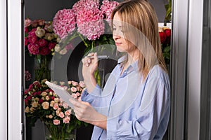 Smiling young woman florist small business flower shop owner checking orders.