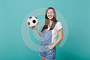 Smiling young woman football fan support favorite team holding soccer ball isolated on blue turquoise background in