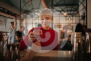 Smiling young woman getting drinks in a bar at night