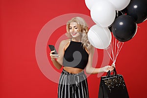 Smiling young woman girl in black clothes posing isolated on bright red background. Shopping discount sale concept. Mock