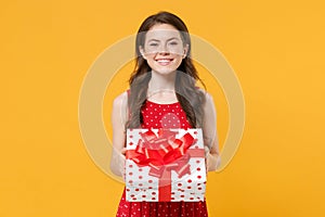 Smiling young woman girl in red summer dress posing isolated on yellow wall background studio portrait. Birthday holiday