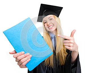 Smiling young woman in graduation gown pointing on book