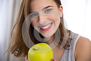 Smiling young woman with green apple