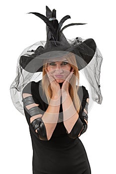 Smiling young woman with green eyes looks in camera, black witch hat. Halloween party, white background. Young witch, vertical