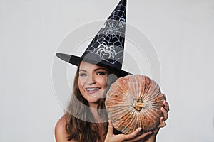 Smiling young woman in Halloween witch hat with pumpkin