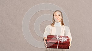 A smiling young woman hands a present to the viewer