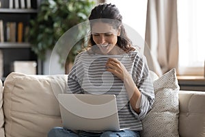 Smiling young woman have fun using laptop at home