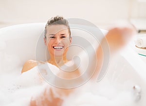 Smiling young woman having fun time in bathtub