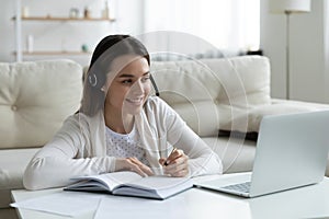 Smiling young woman in headphones looking at laptop screen